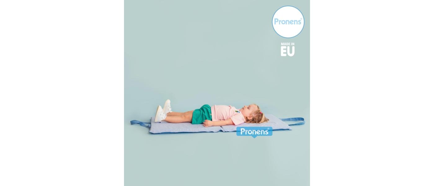 Niña de 3 años estirada sobre márfega colchoneta escolar